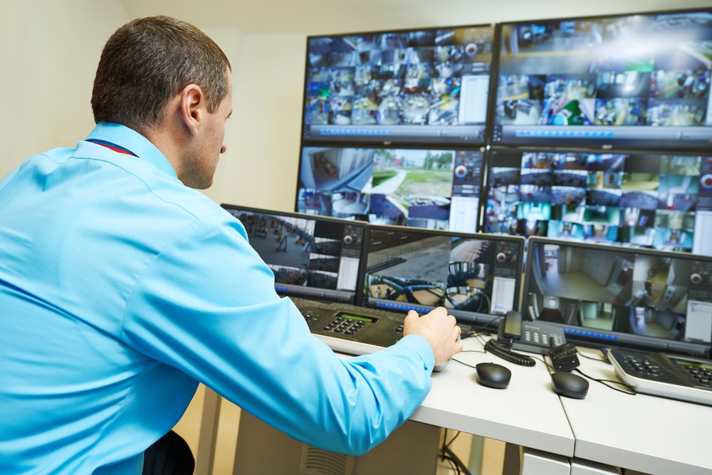 Security operator reviewing video surveillance footage on a wall of monitors